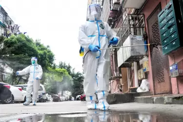 Voluntarios que usan equipo de protección personal desinfectan una comunidad residencial en el distrito de Yangpu, en Shanghái, China.