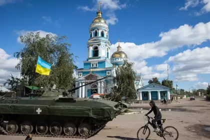 Un niño monta en bicicleta cerca de un tanque blindado con una bandera ucraniana en la ciudad de Izium, recientemente liberada por las Fuerzas Armadas