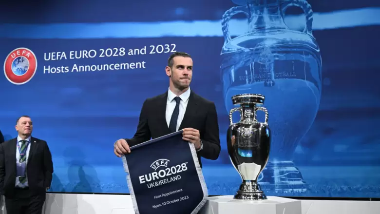 El exfutbolista gals Gareth Bale sostiene el bandern de la Eurocopa 2028 tras el anuncio de su concesin a Reino Unido e Irlanda
