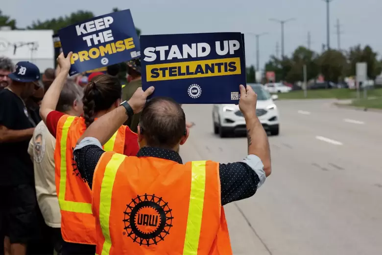 Trabajadores de la UAW con pancartas que dicen: "Lévantate Stellantis".