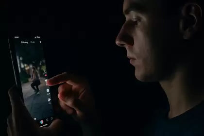Usuario deslizando el feed de TikTok en un entorno oscuro, simbolizando el scroll infinito
