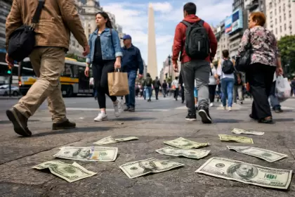 Gente camina por el centro de Buenos Aires mientras varios billetes de dólares yacen en el piso, ignorados por los peatones.