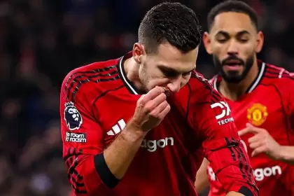 Diogo Dalot besándose el escudo del United en pleno festejo de gol, con Matheus Cunha de fondo acompañándolo.